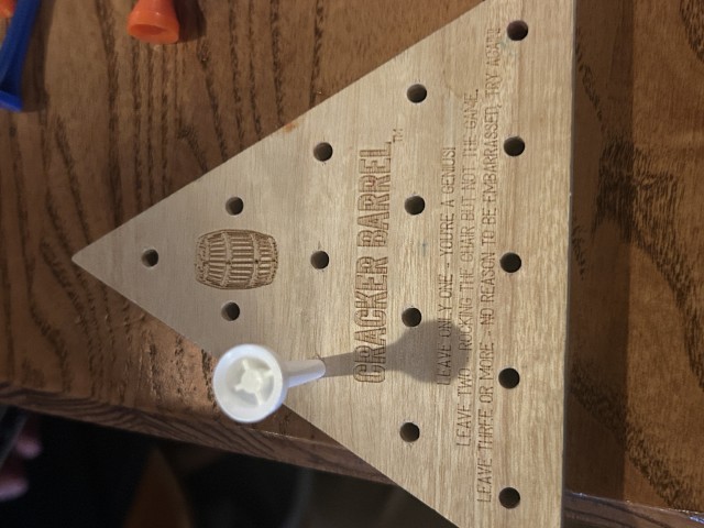 Finished Cracker Barrel peg game with only one peg remining. The board says that I am a genius.